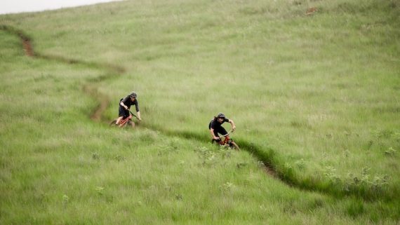 Two mean ride Specialized mountain bikes on grassy singletrack in South Africa