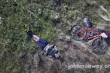 Gravel cyclist laying next to his bike loaded with gear