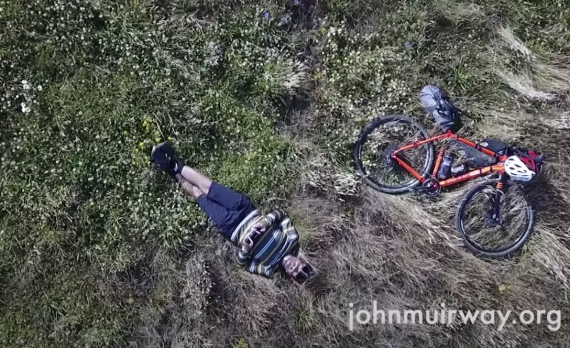 Gravel cyclist laying next to his bike loaded with gear