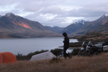 Two motorcycle riders set up their tents while camping in New Zealand