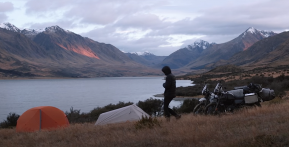 Two motorcycle riders set up their tents while camping in New Zealand