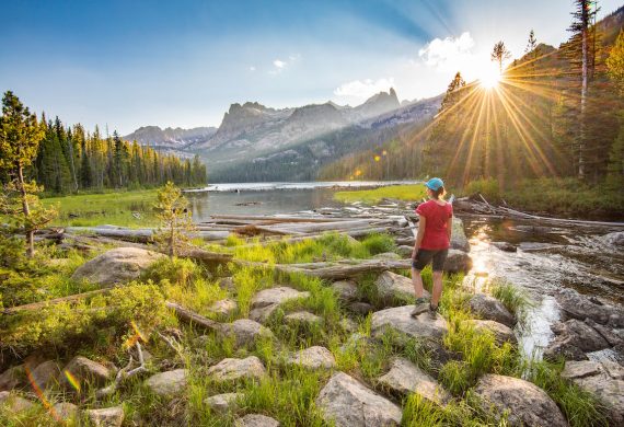 female hiker watches the sunset while standing on rocks near the Sawtooth Mountains in Idaho