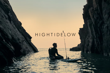 Man sitting on his paddle board with a fishing pole in the ocean