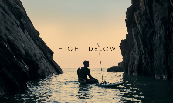 Man sitting on his paddle board with a fishing pole in the ocean