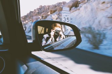 A man taking pictures from the car's passenger window while driving through the California Desert on a camping trip