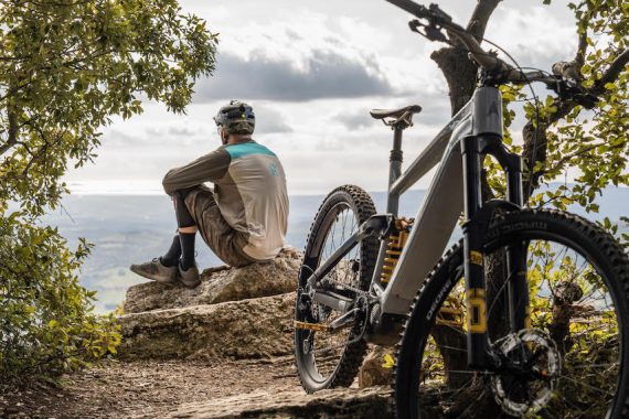 Mountain biker Rob Warner sits on rock next to his E-MTB