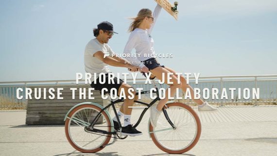 A man riding his Priority x Jetty beach cruiser with a girl on the handlebars