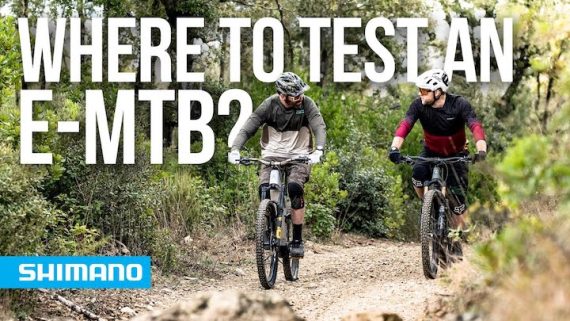 Two men riding an E-MTB on a dirt trail