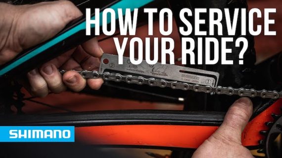 A man holding a wrench next to his bike chain while repairing the bike