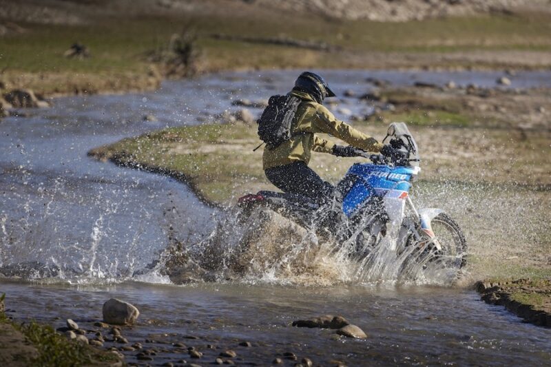 A rider takes his Aprilia Tuareg 660 across a stream.