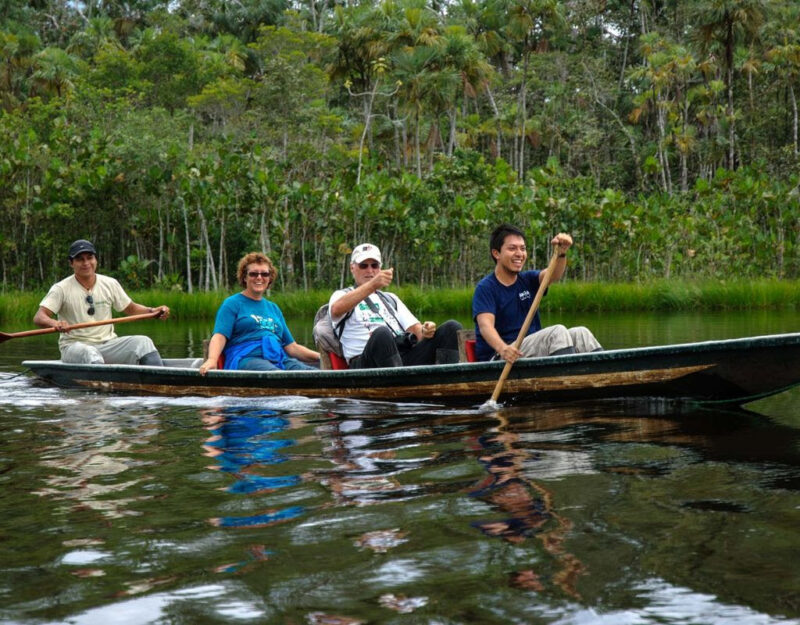 A group of older adults in a long paddle boat on The Amazon