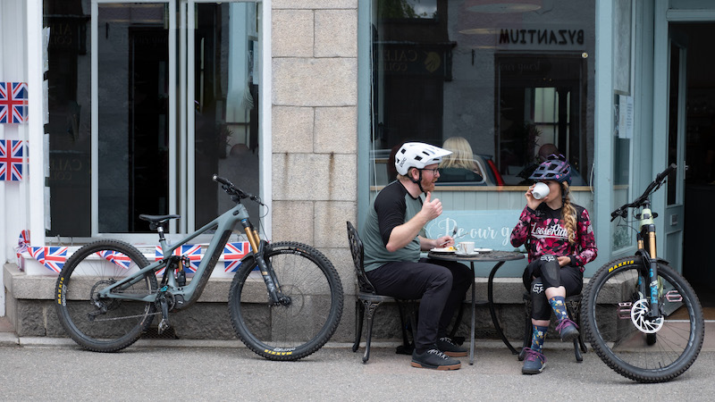 Two mountain bikers enjoying a lunch break at an outdoor cafe with their bikes beside them. mountain bikes