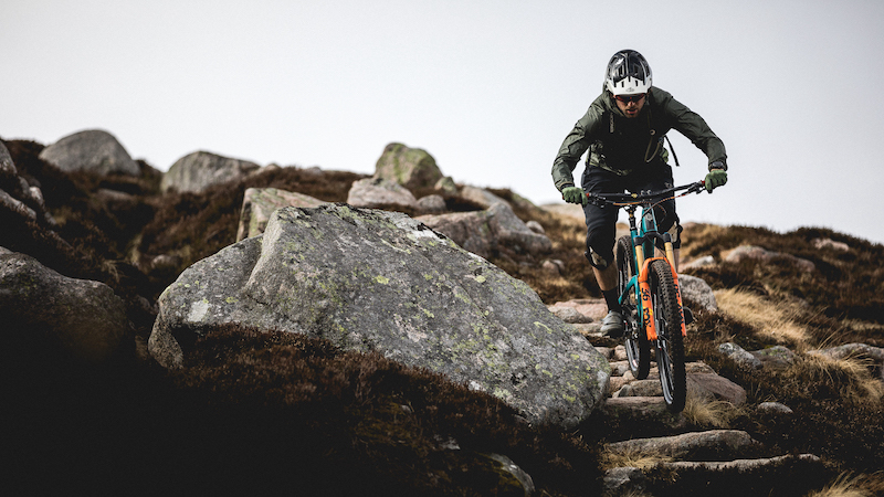 A single mountain biker riding down steps made of rock during an E-MTB adventure in the Scottish Highlands.