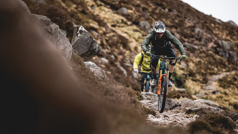 Two mountain bikers climbing rocky singletrack while on an E-MTB adventure in the Scottish Highlands.