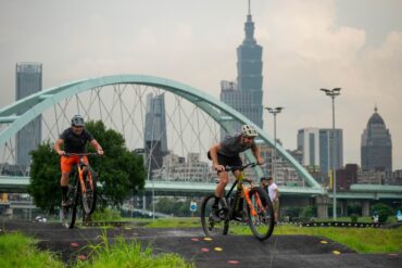 Two male mountain bikers riding an urban pump track in Taipei.