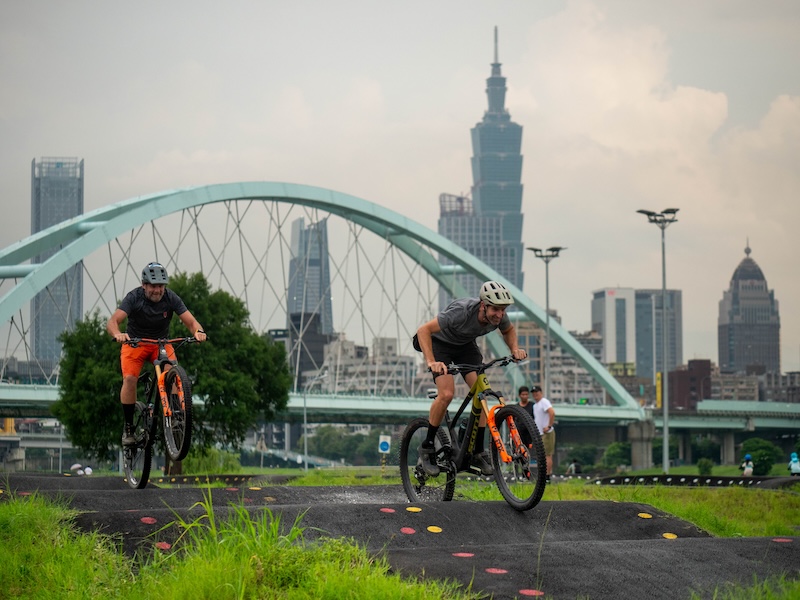 Two male mountain bikers riding an urban pump track in Taipei.