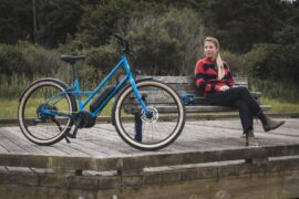 A young female in plaid and jeans admiring her Markin Larkspur E from a park bench