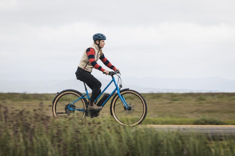 A female cyclist riding the Marin Larkspur E on a paved bike trail