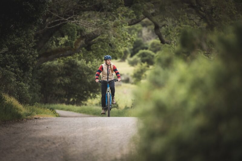 A female cyclist riding the Marin Larkspur E on a dirt road in the countryside.