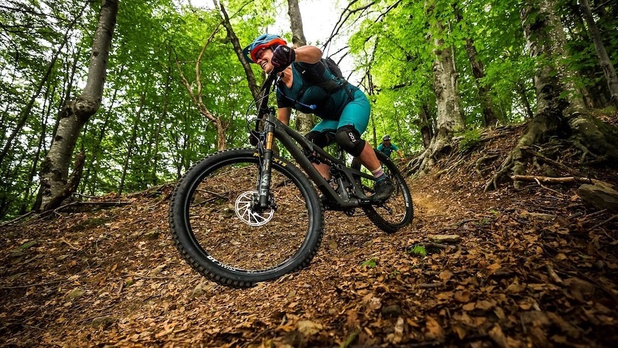 A female mountain biker shreds downhill single track on a tree-lined trail in Alabama.